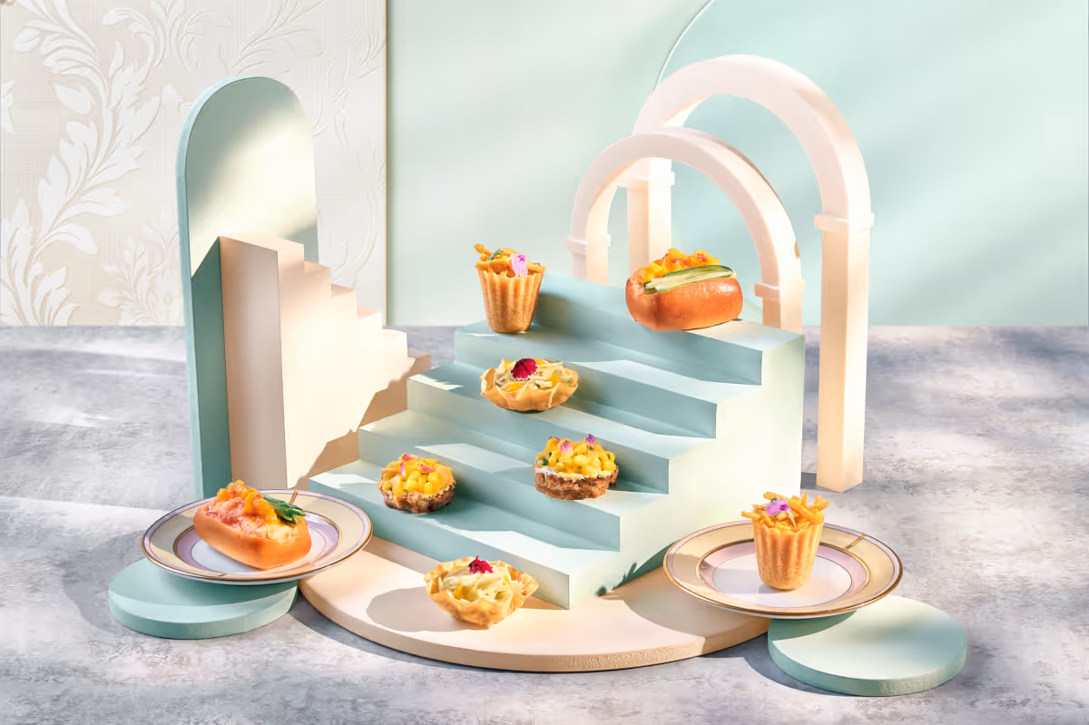 Creative food display with small gourmet appetizers on pastel blue stairs and plates under soft light.