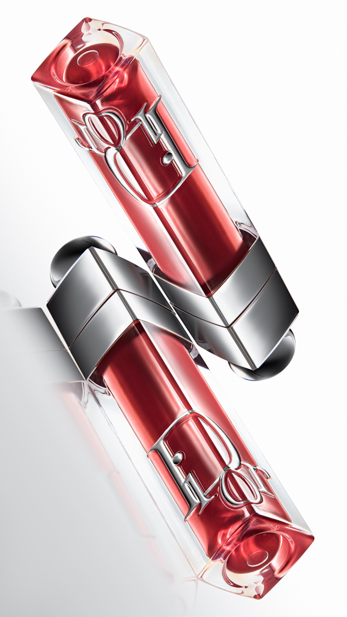Two Dior lip gloss tubes with red liquid and silver caps on a white background.