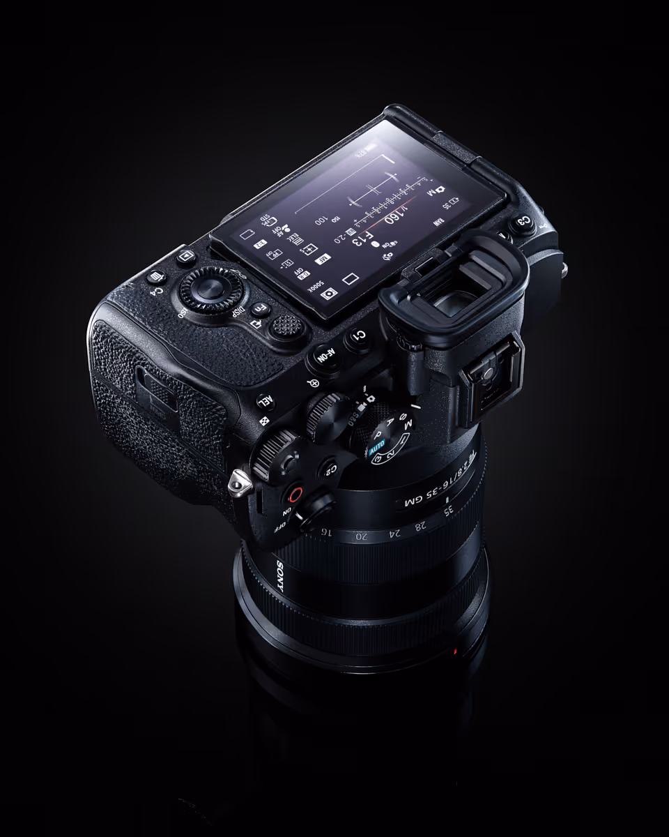 Close-up of a Sony digital camera with settings shown on the flip-up LCD screen, on black background.