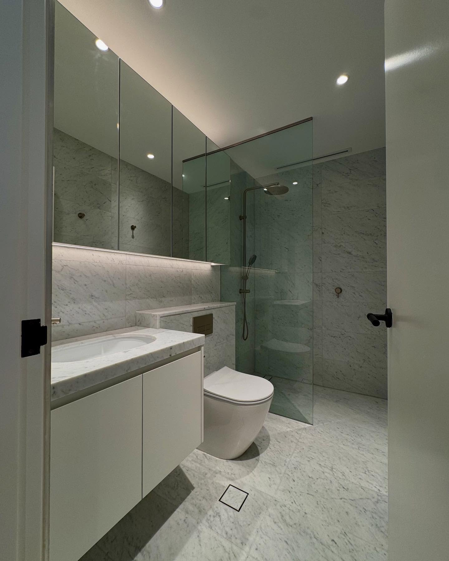 Stone finishes and frameless shower glass in the main bathroom.