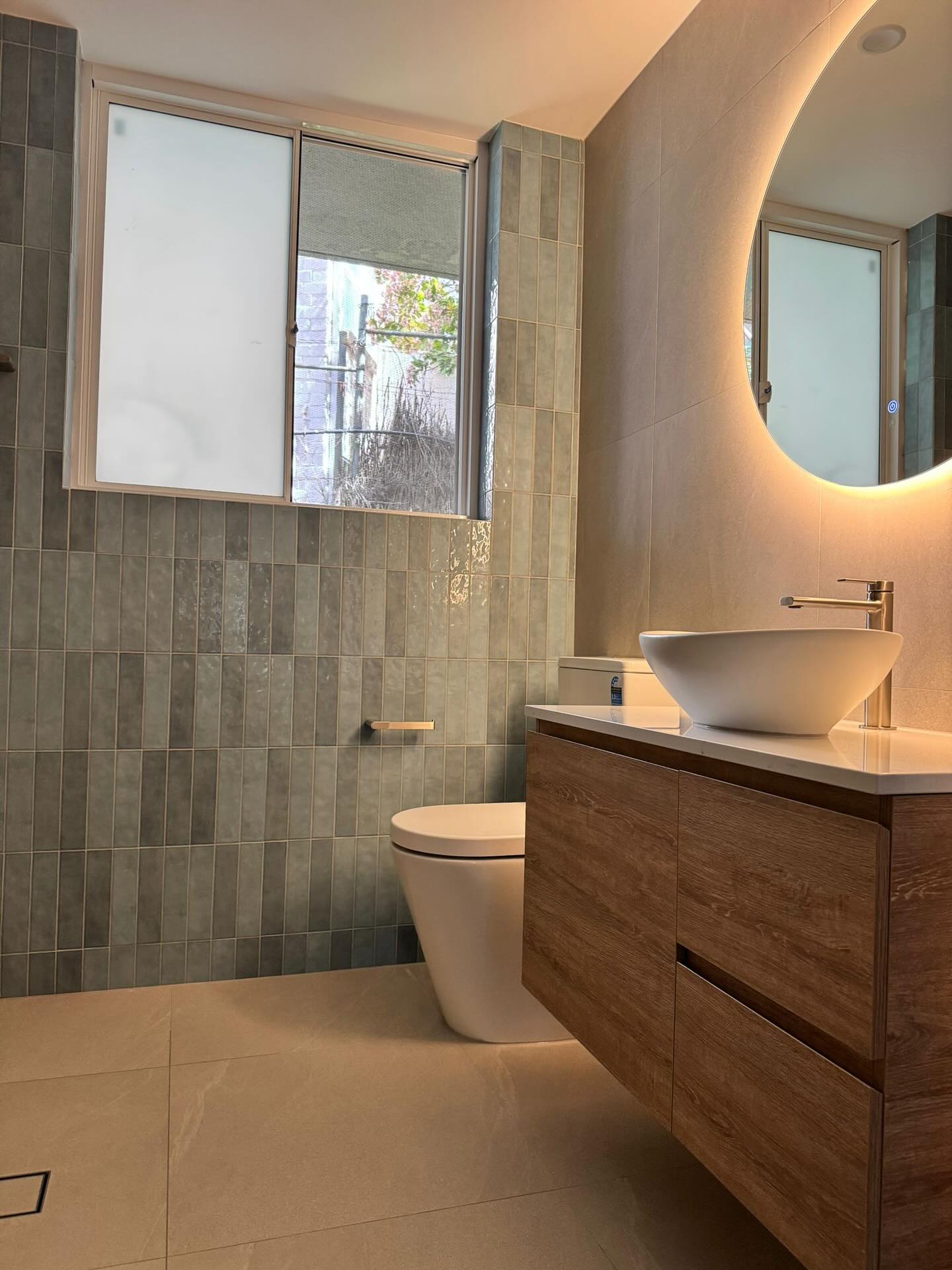 Textured wall tiles paired with warm timber vanity joinery.