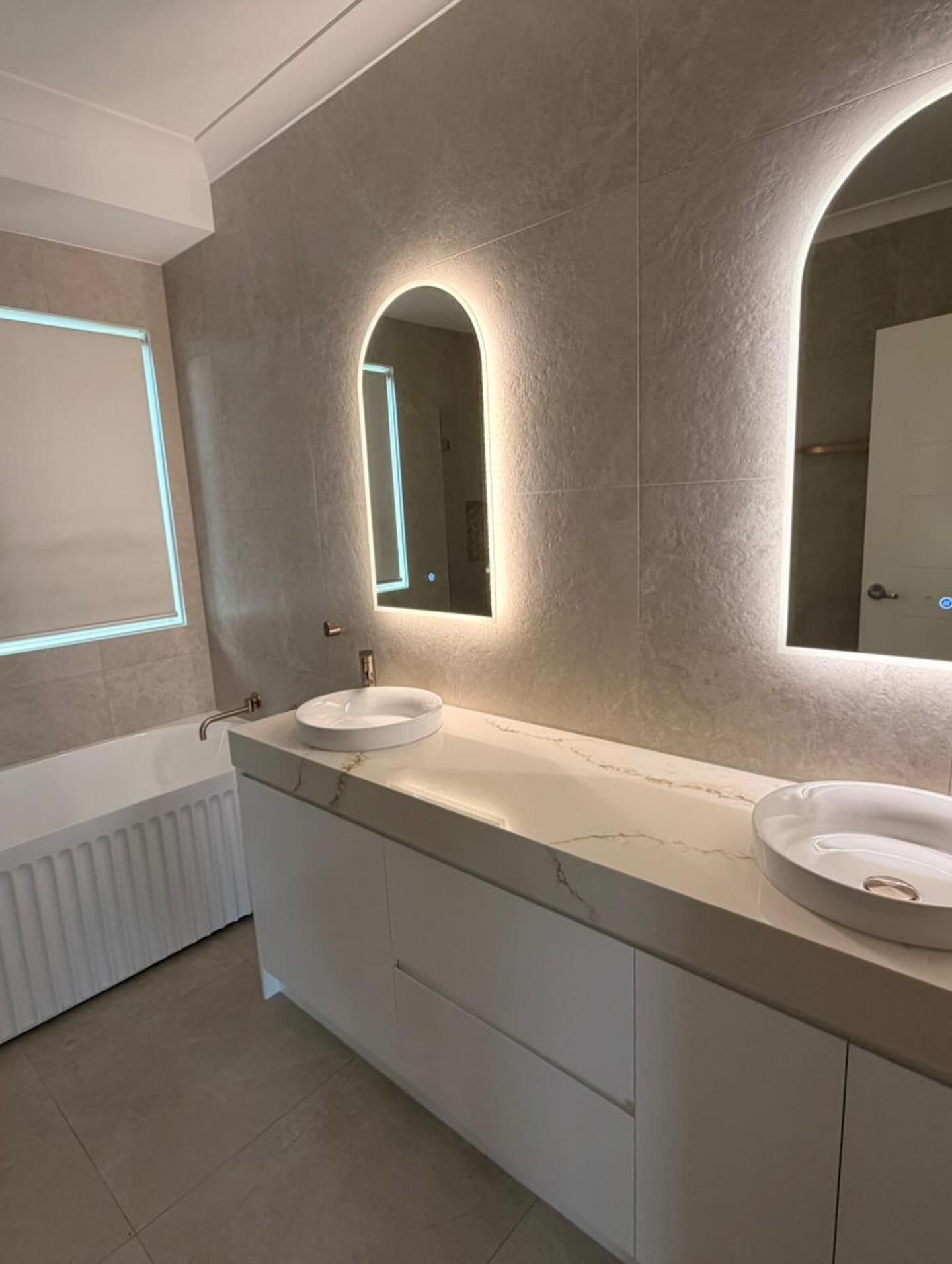 Double vanity and illuminated arched mirrors.