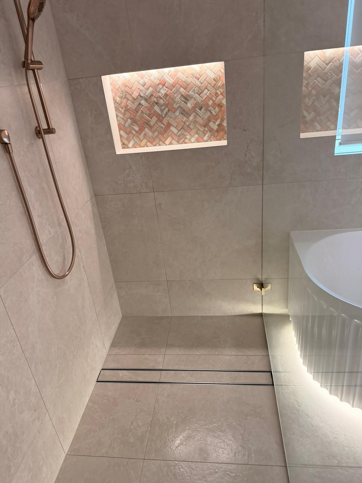Walk-in shower with illuminated wall niche.