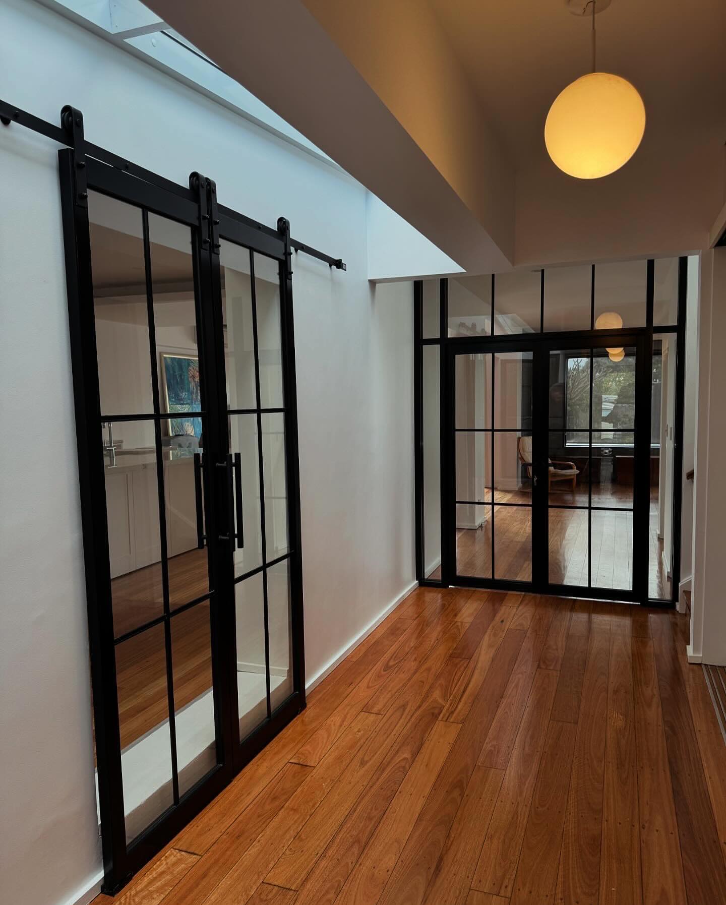 Aluminium-framed barn doors paired with restored timber floors.