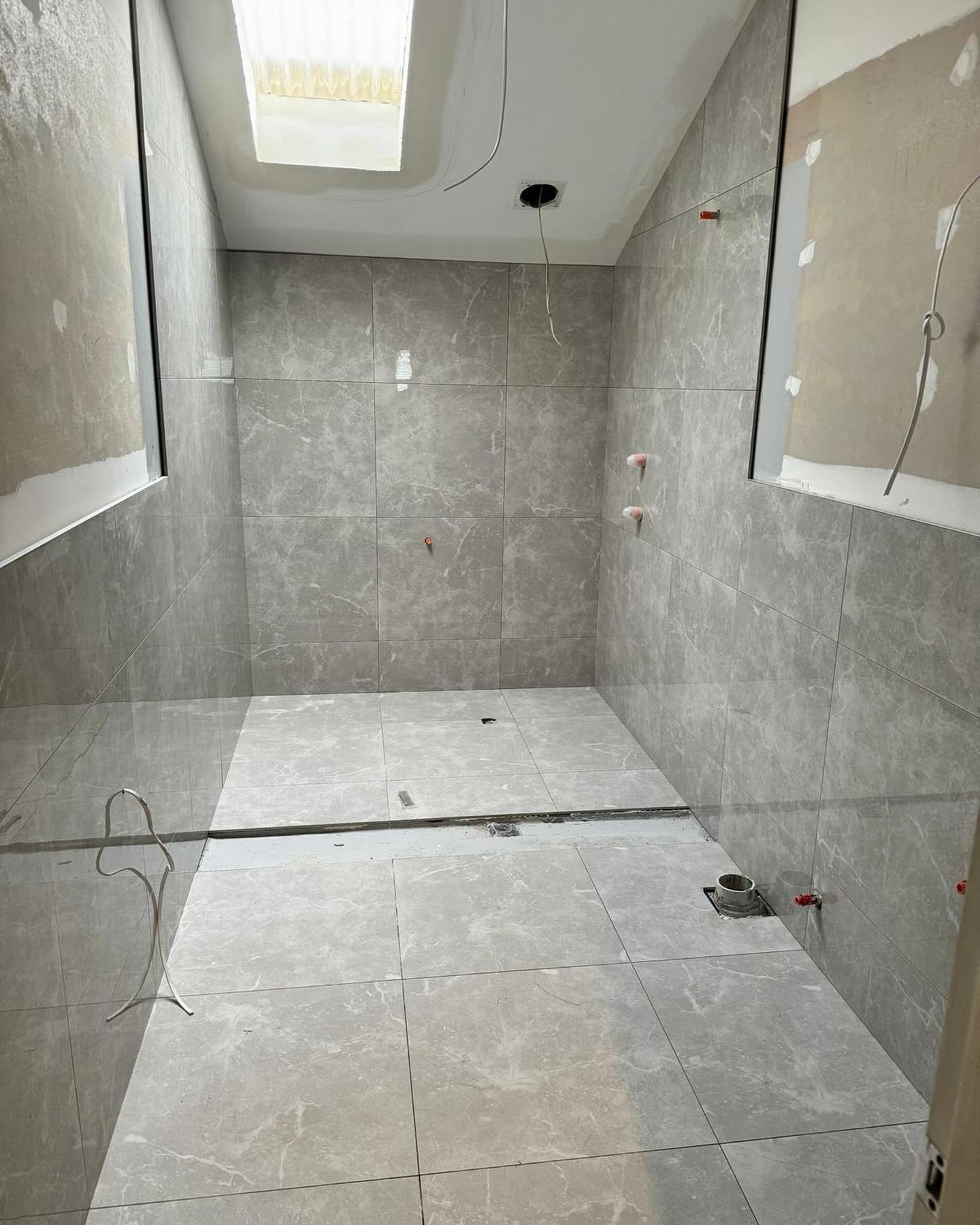 Bathroom wall and floor tiling in progress.