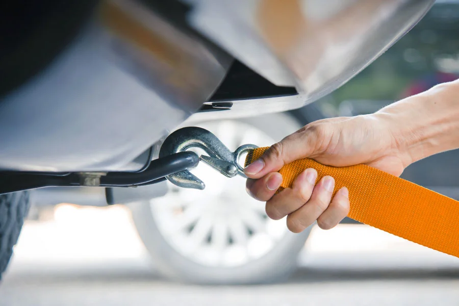 Recovery hook and orange strap attached to a vehicle towing point.