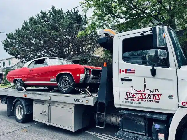 Red classic convertible on a Norman Towing flatbed truck.