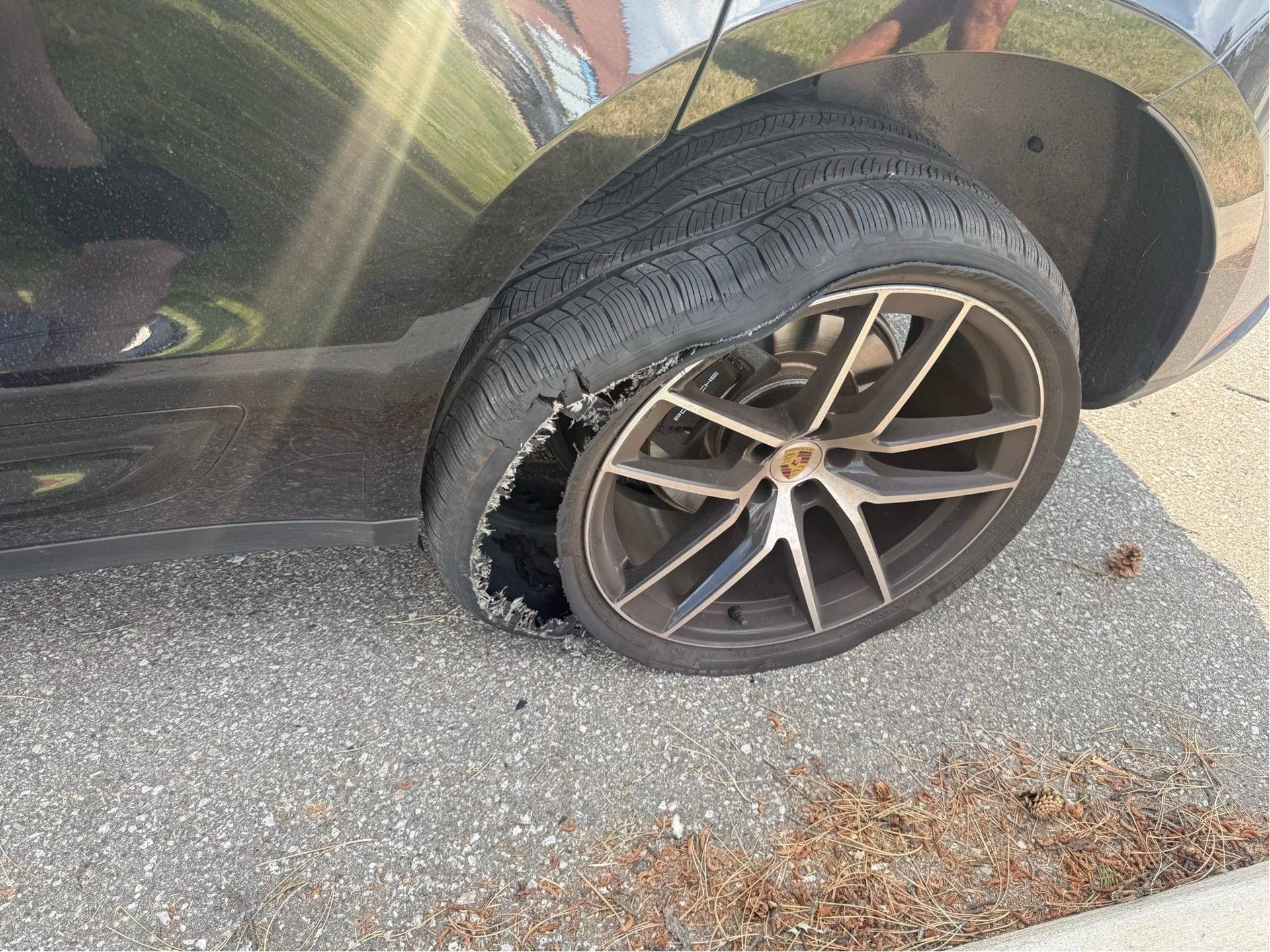 Shredded tire on the front wheel of a Porsche SUV.