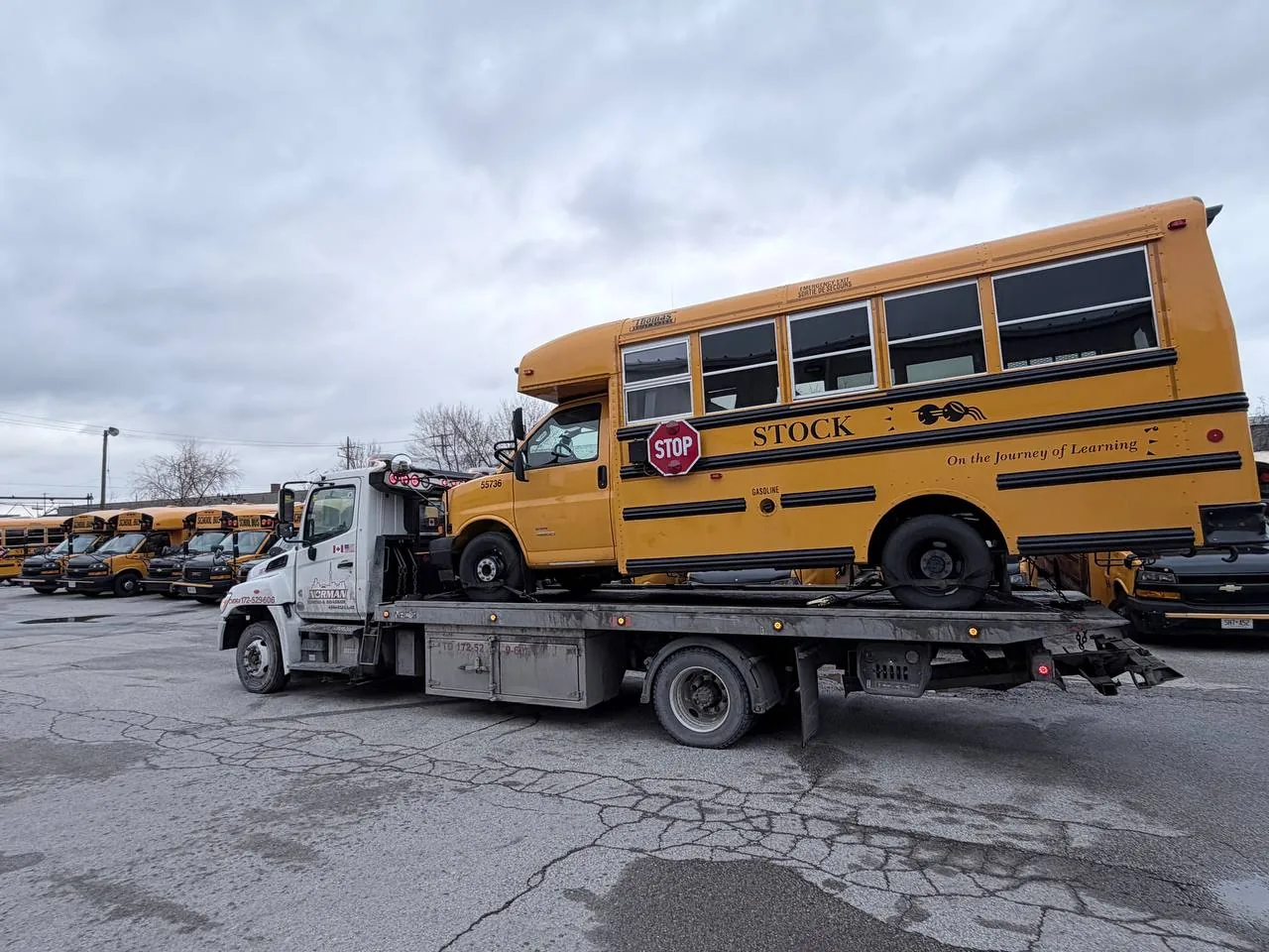 Yellow school bus carried on a flatbed tow truck.