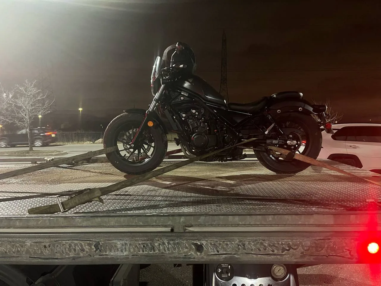 Motorcycle on a flatbed tow truck deck at night