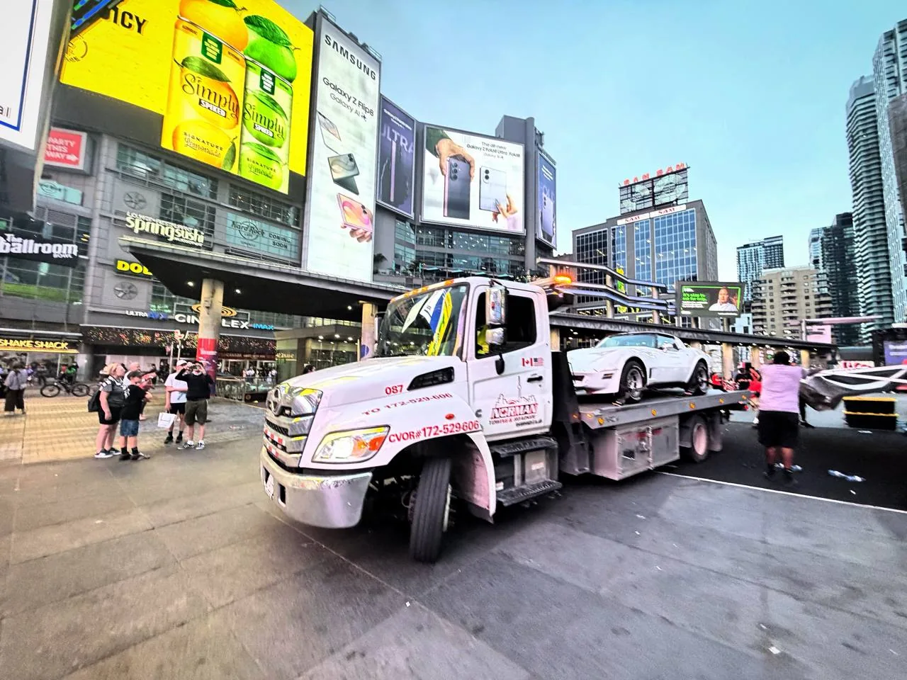Norman Towing flatbed carrying a vehicle at Yonge-Dundas Square.