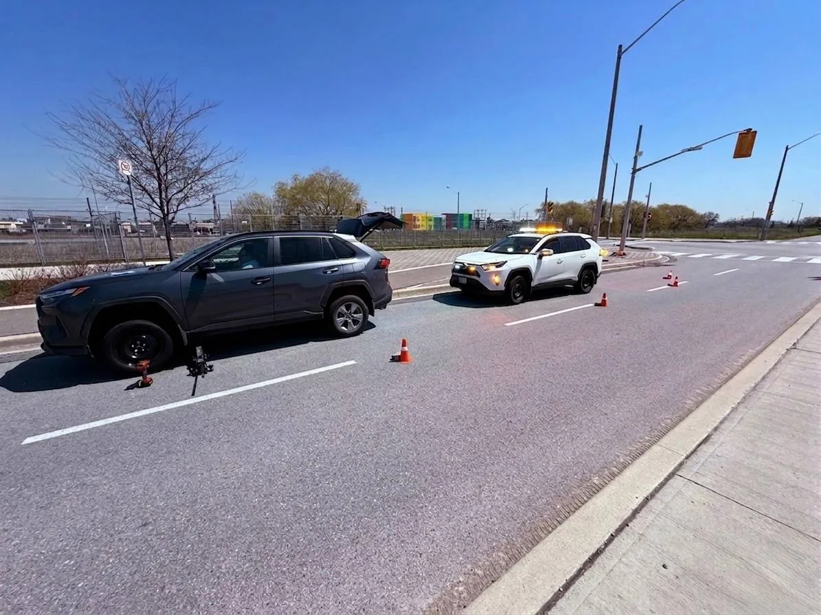 SUV and emergency vehicle beside traffic cones on a road shoulder.