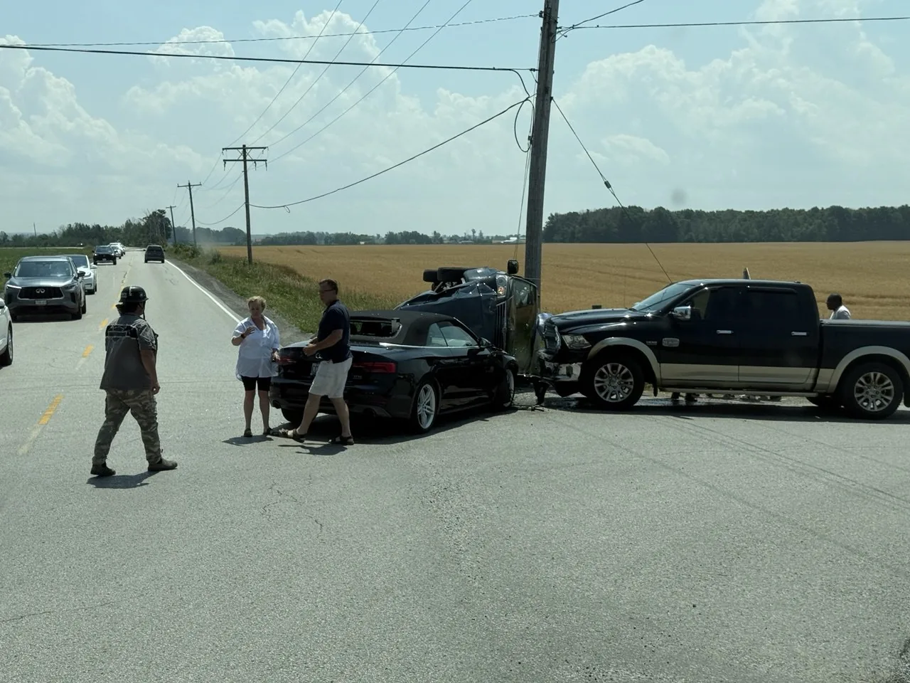 Vehicles and people gathered beside a rural road during roadside assistance.