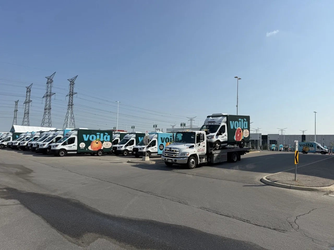 Norman Towing flatbed beside a fleet of branded delivery vans.