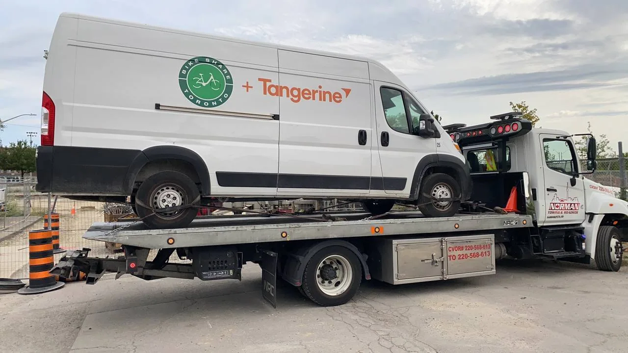 Branded white cargo van secured on a Norman Towing flatbed.