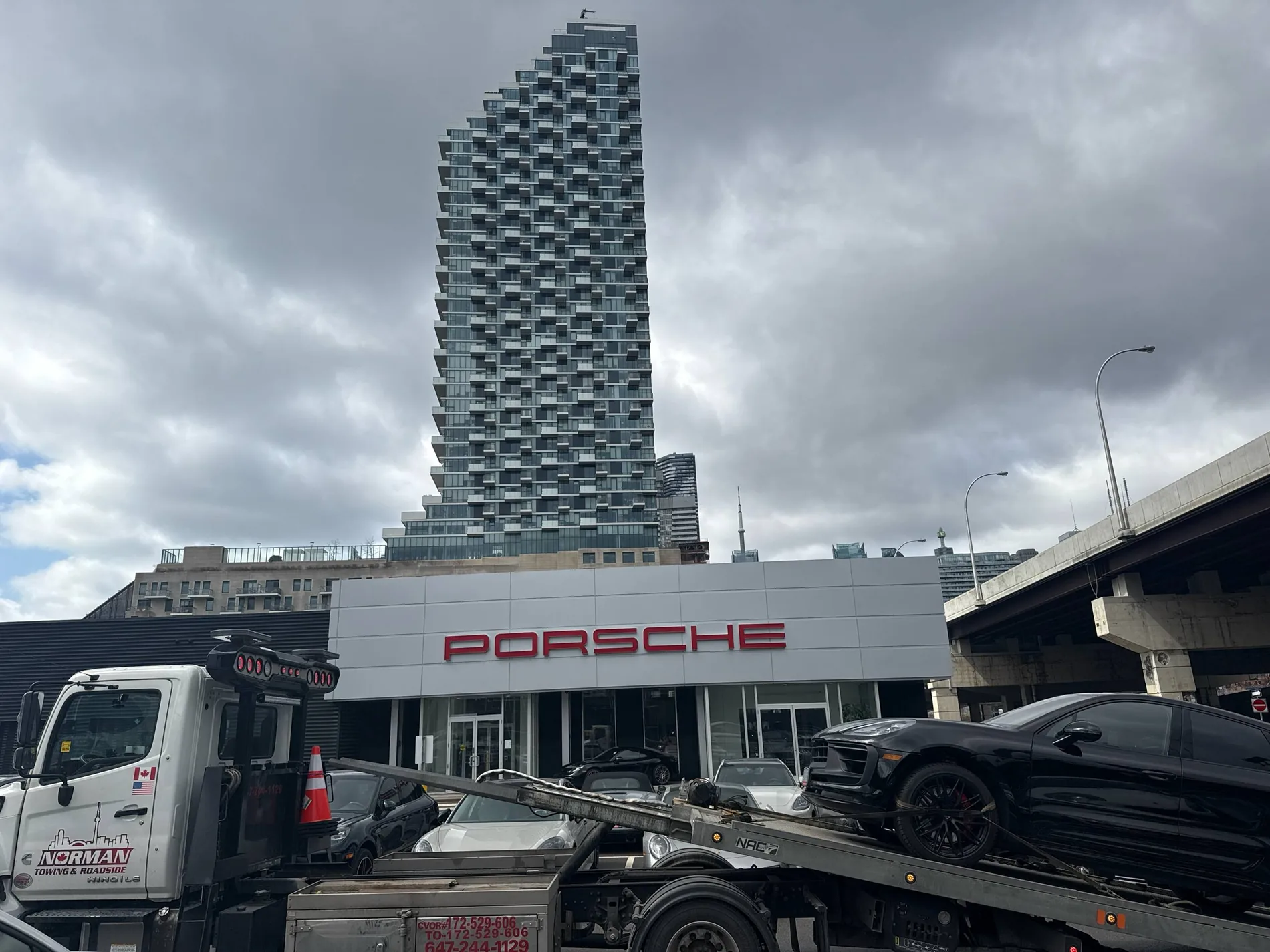 Norman Towing flatbed outside a Porsche dealership.