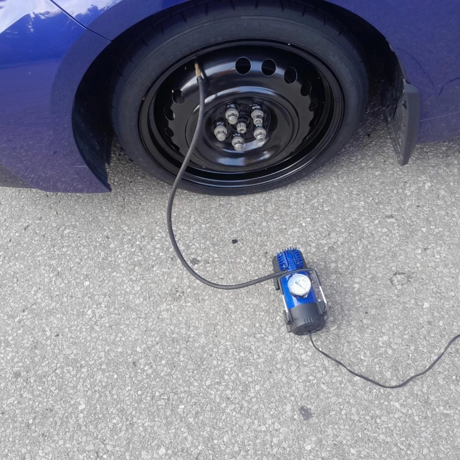 Portable air compressor inflating a vehicle tire during roadside assistance