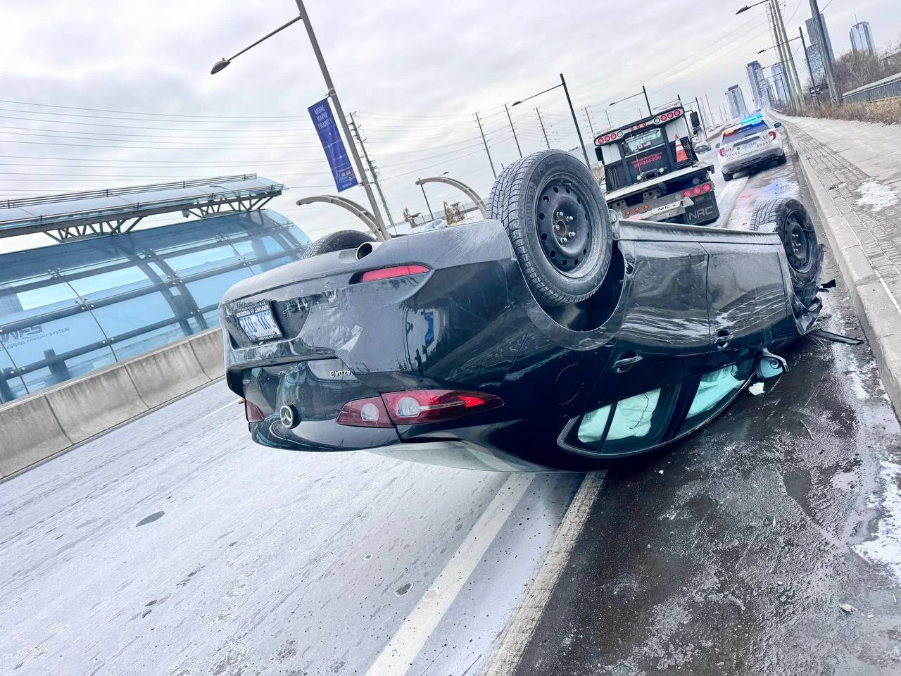 Overturned Mercedes vehicle on a wet roadway.