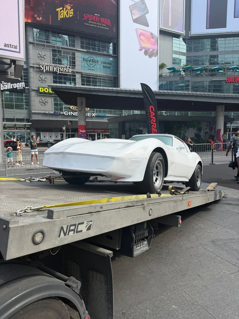 White classic Corvette on a flatbed in downtown Toronto.