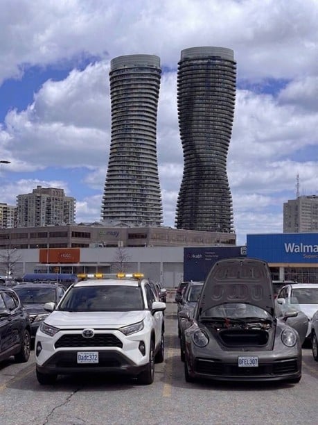 Norman Towing providing roadside assistance (battery boost) to a Porsche in Mississauga — with the iconic Absolute World towers in the background. | normantowing.ca