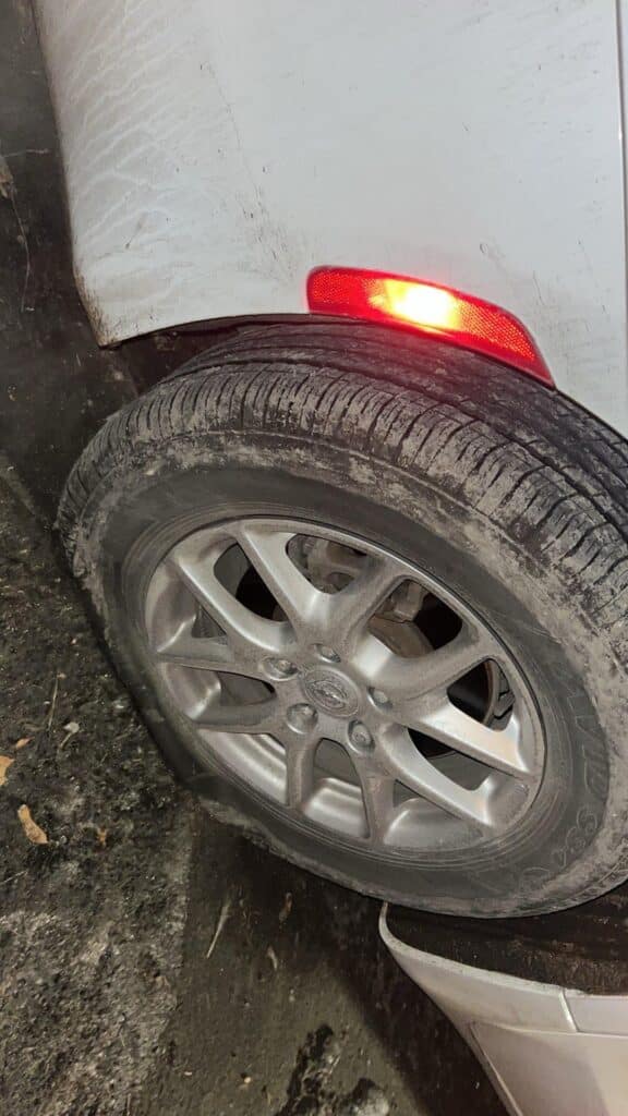 Flat Michelin tire on a white Chrysler Pacifica with factory 17-inch silver alloy wheels.