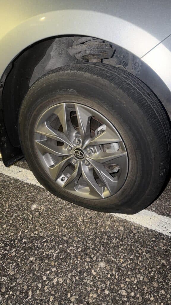 Flat tire on a silver Toyota Corolla with 5-lug alloy wheels in a Toronto parking lot.