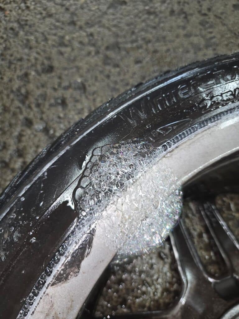 Side view of a silver 2014 Mercedes-Benz E350 Cabriolet with a flat tire in an underground parking garage.