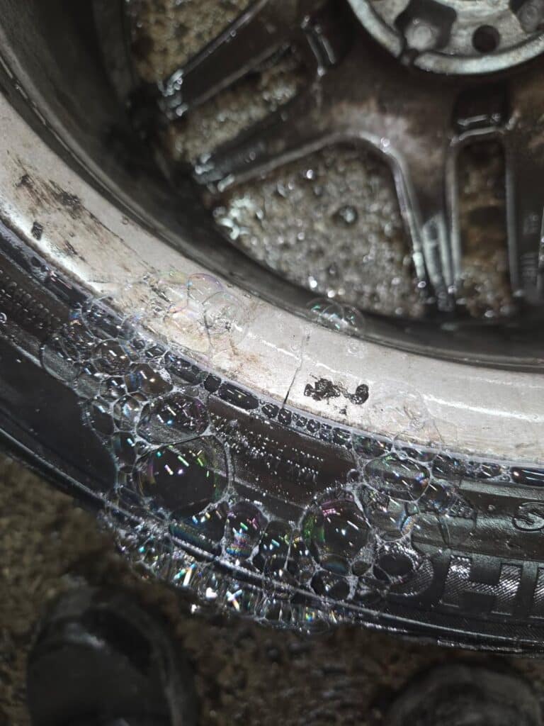 Close-up of a flat tire on a Mercedes-Benz AMG-style alloy wheel inside a low-clearance garage.
