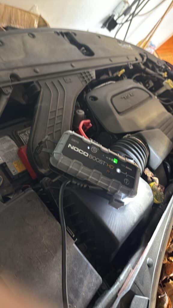NOCO Boost HD GB70 2000 Amp jump starter connected to a Chrysler Pacifica 3.6L Pentastar V6 engine battery.