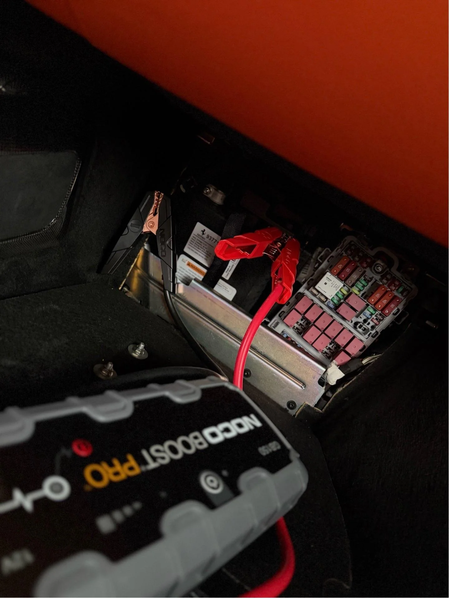Portable battery booster connected to a vehicle battery during roadside battery boost service