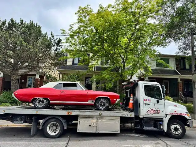Red classic convertible transported on a Norman Towing flatbed.