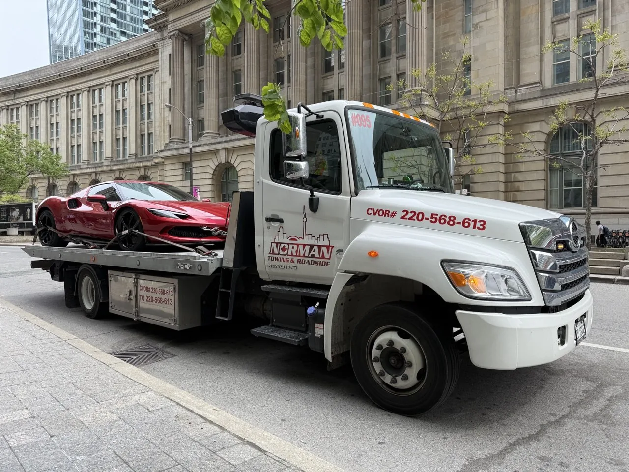 Red Ferrari on a Norman Towing flatbed near Toronto Old City Hall.