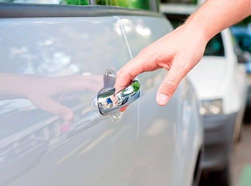 Hand reaching for a car door handle.