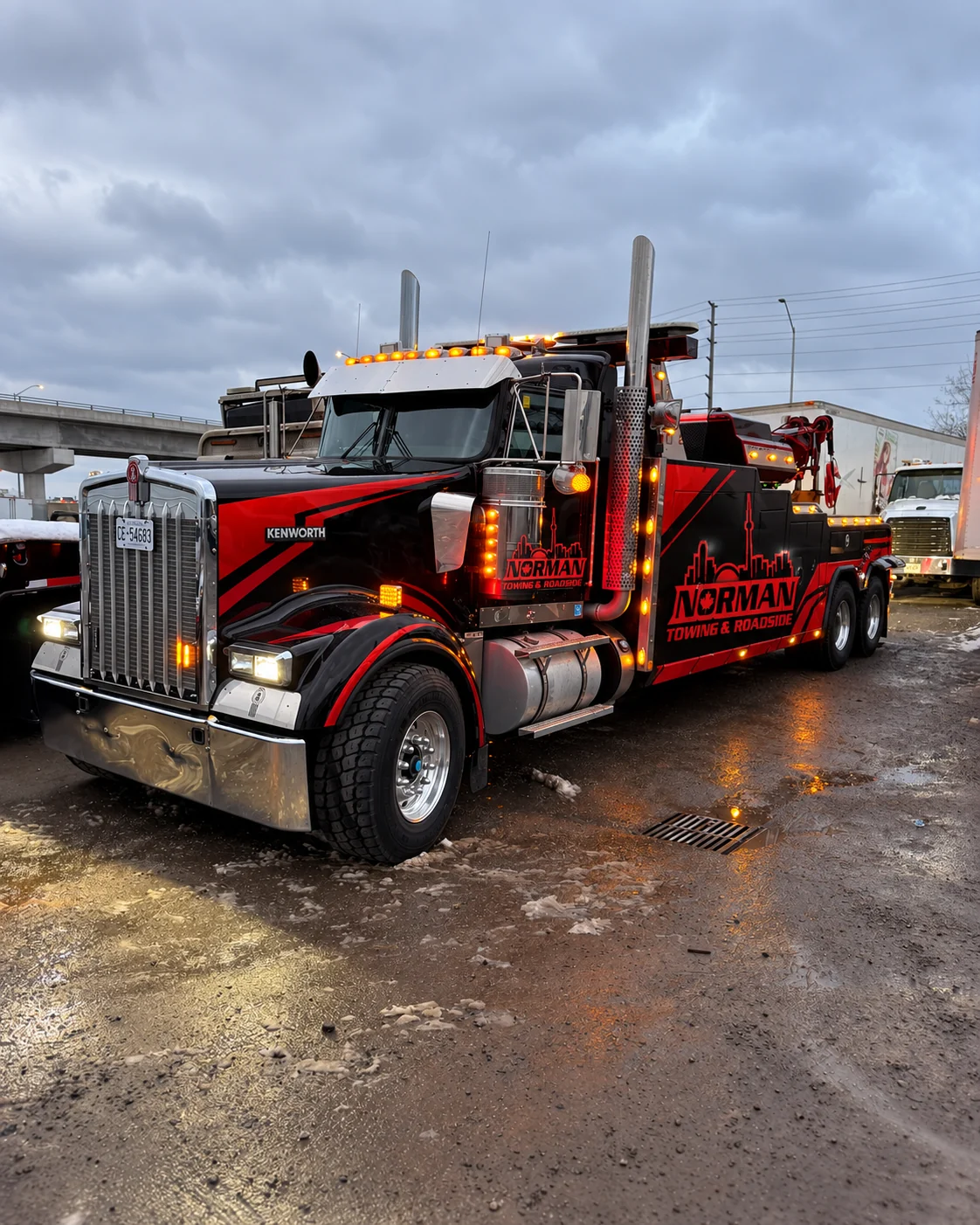 Heavy Duty Wrecker Service | Norman Towing Norman Towing heavy duty wrecker truck with red and black branding parked in a yard at dusk.