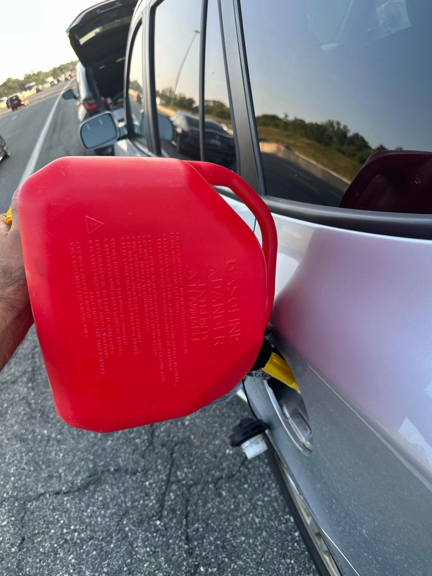 Emergency Gas Delivery Service | Norman Towing Red gas can being used to deliver fuel to a silver vehicle on the roadside.