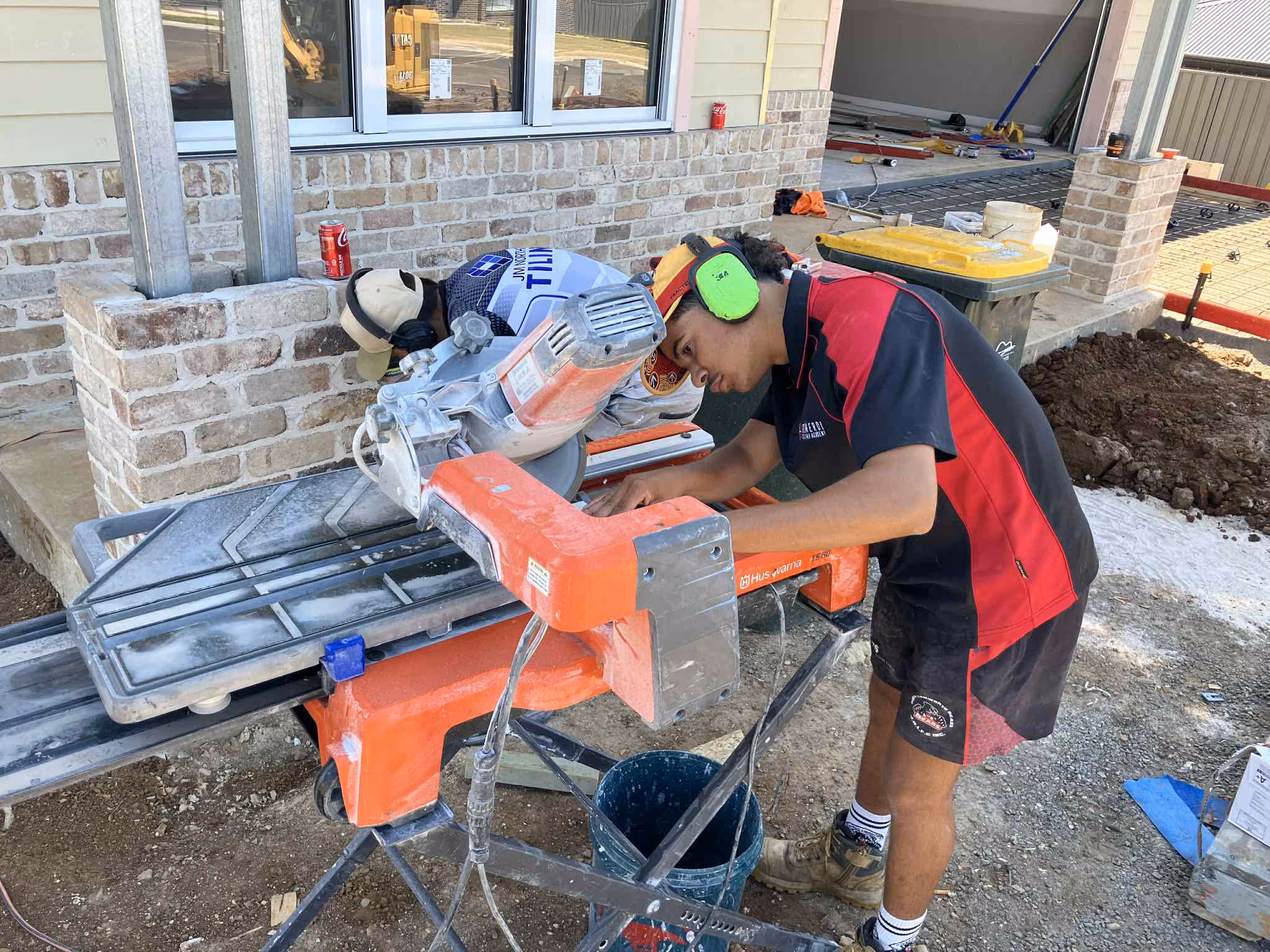 A young man used machinery to cut down tile for a job.