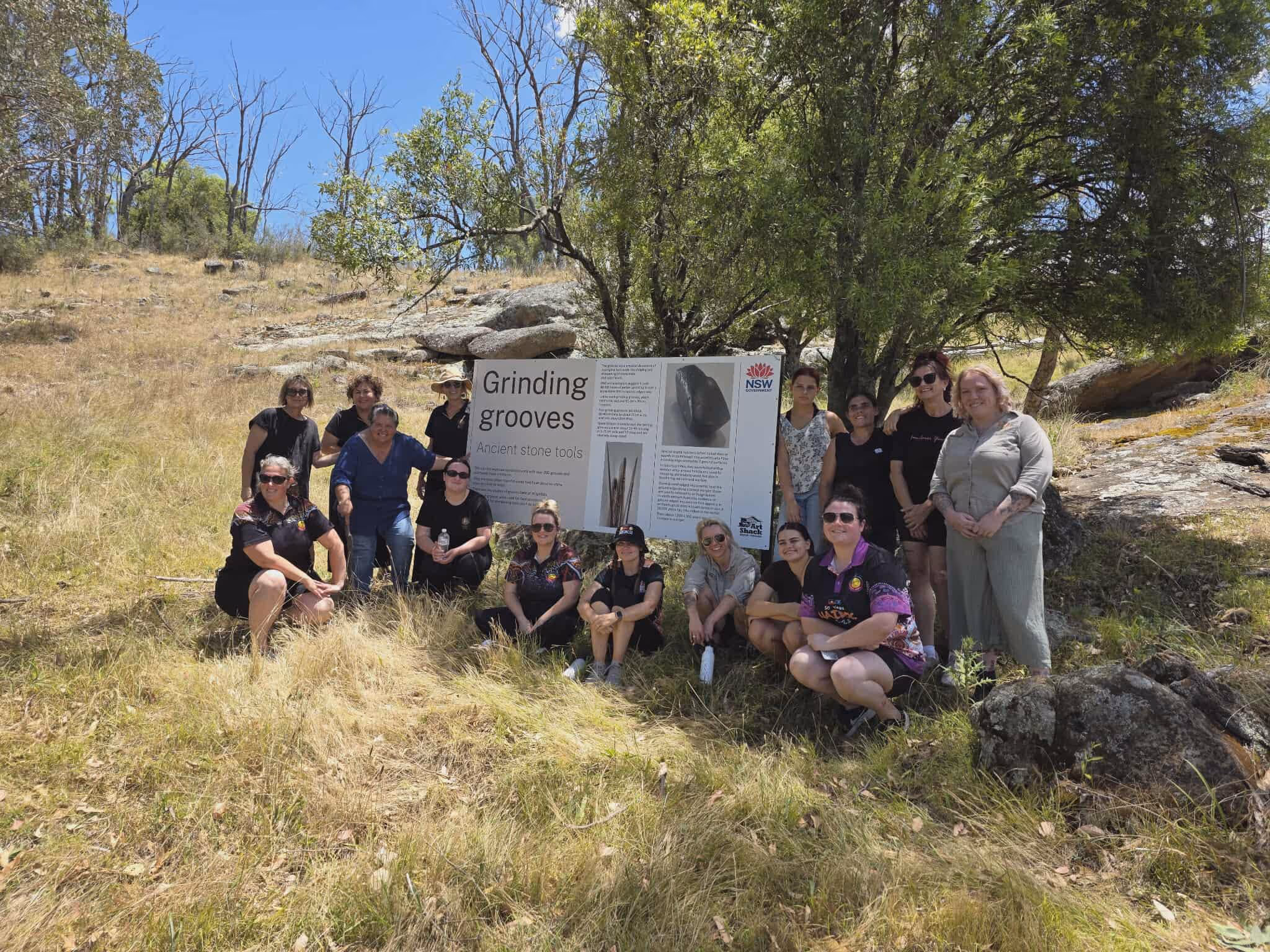 Women are outside in the shade of a tree on a hill