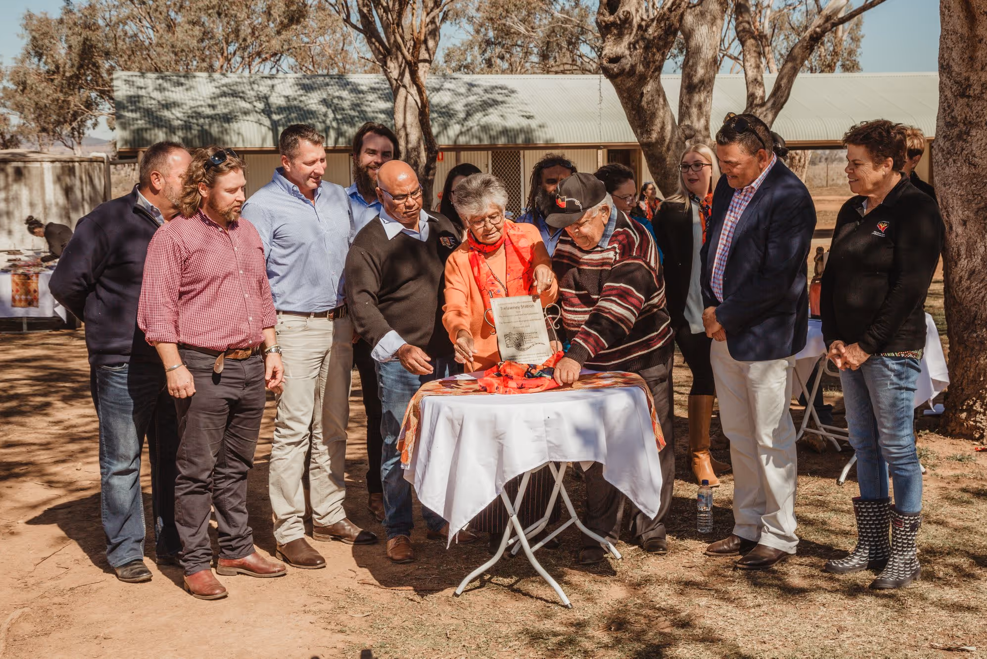 Community members and Elders gather around a table outside