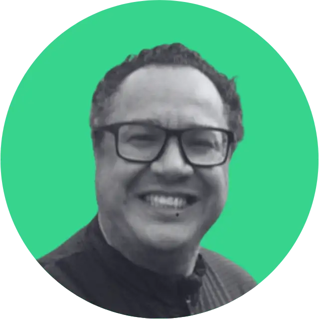 Smiling man with glasses and curly hair against a green circular background.