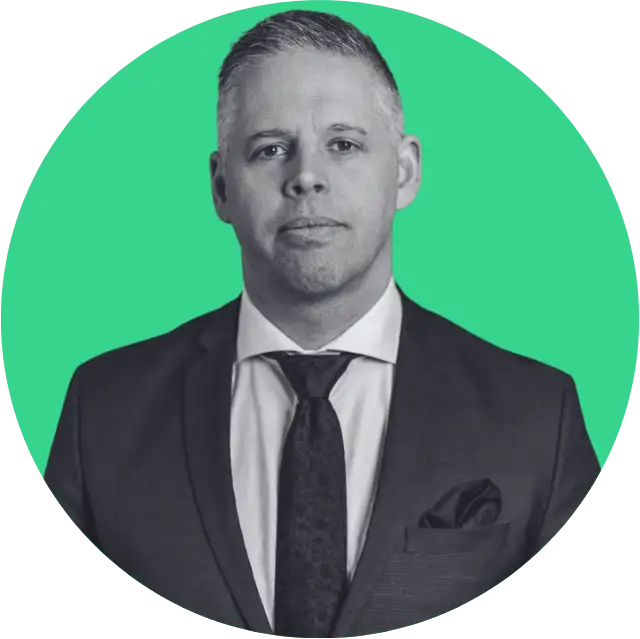 Man in a suit and tie with a pocket square against a green circular background.