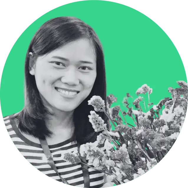 Smiling woman with shoulder-length hair holding a bouquet of flowers against a green background.