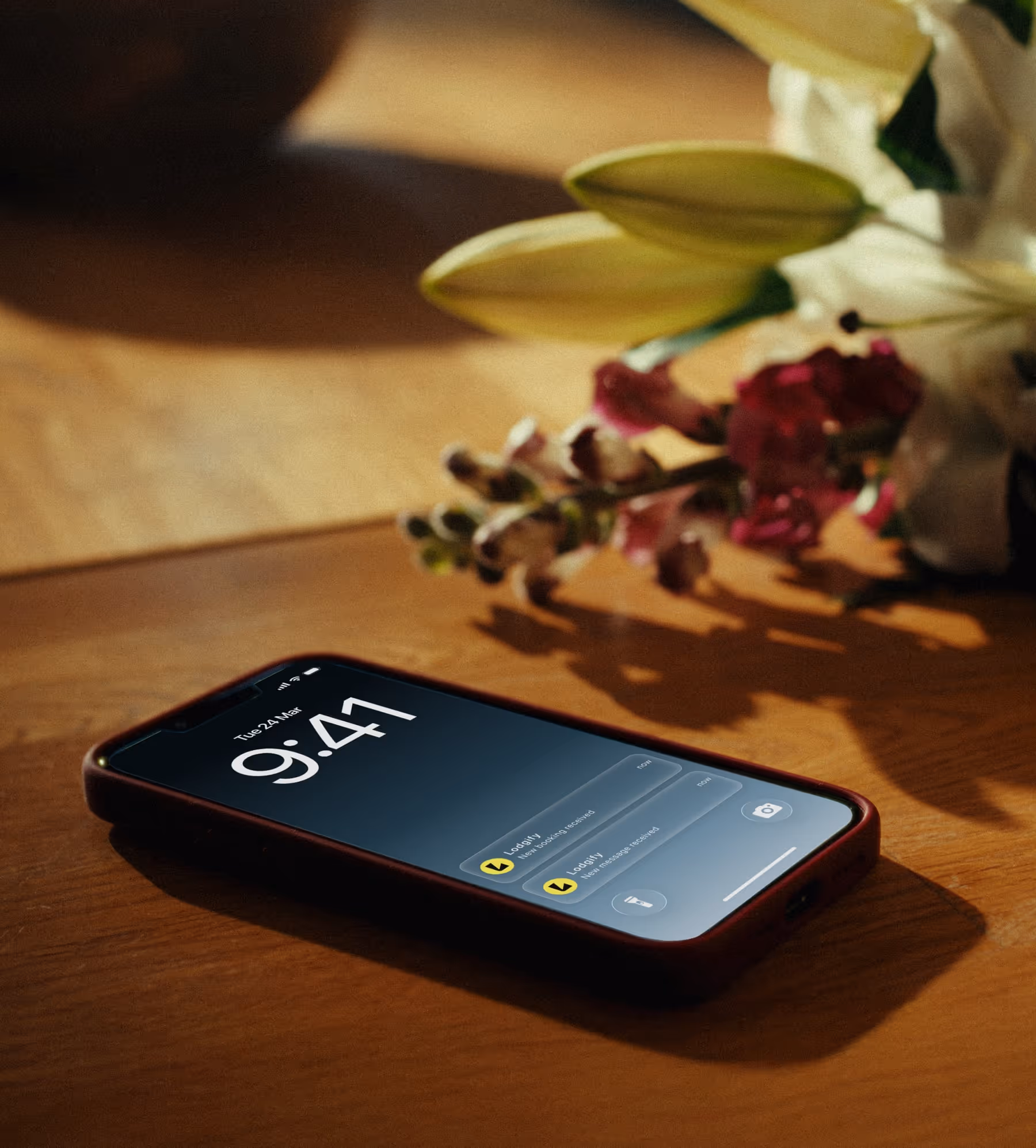 Smartphone on a wooden table screen showing the time 9:41 and notifications from Lodgify app.