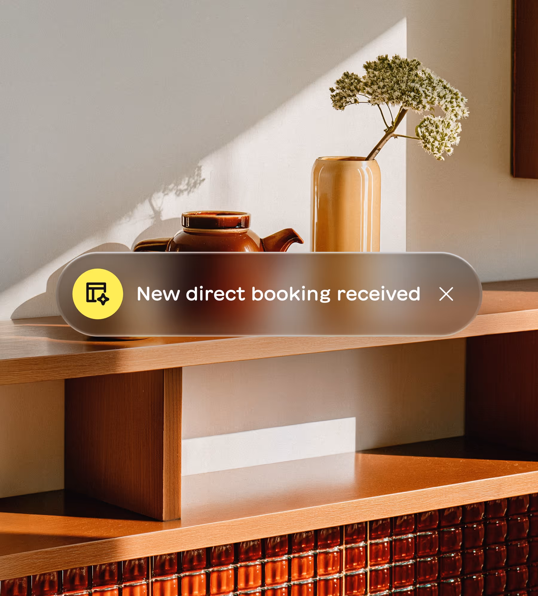 Notification banner on a wooden shelf with a brown teapot and beige vase holding white flowers, reading 'New direct booking received.'
