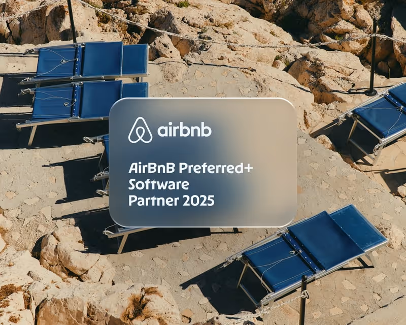 Blue lounge chairs on stone pavement surrounded by rocky terrain with an overlay text showing Airbnb logo and text 'AirBnB Preferred+ Software Partner 2025'.