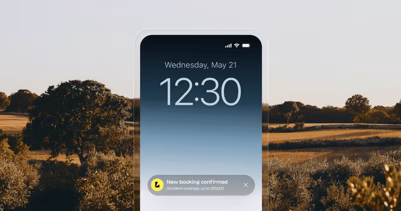 Smartphone screen showing the time 12:30 on Wednesday, May 21, with a notification for a new booking confirmed and accident coverage up to $10,000, set against a background of a sunlit rural landscape with trees and fields.