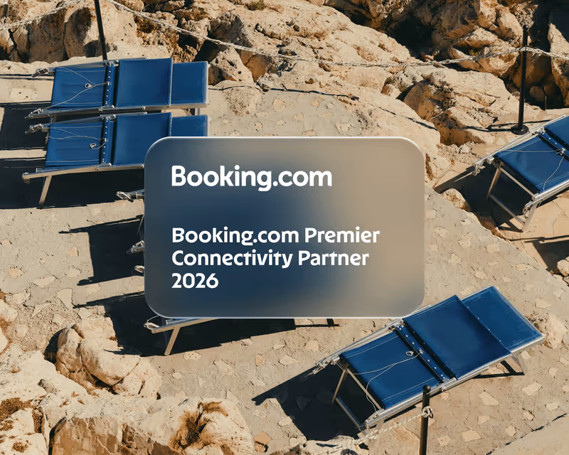 Rocky outdoor area with blue lounge chairs and a translucent overlay announcing Booking.com Premier Connectivity Partner 2026.