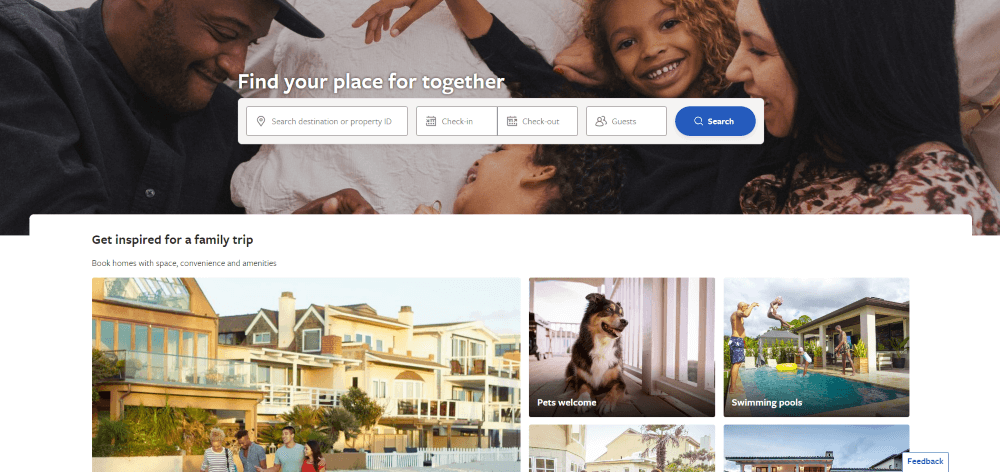 Smiling family of four lying together with vacation home search bar and family trip inspiration below.