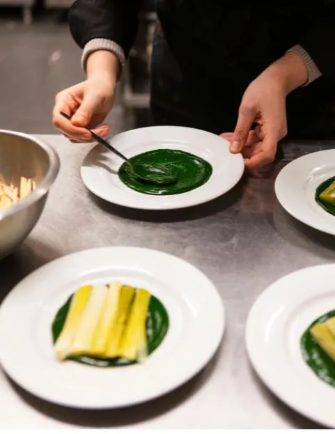 Un pâtissier découpe l'excédent de pâte autour d'un moule à tarte pour préparer une tarte au chocolat.