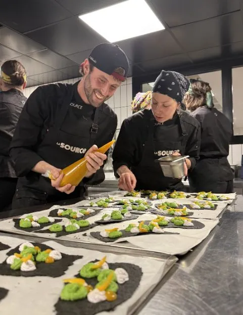 Un pâtissier découpe l'excédent de pâte autour d'un moule à tarte pour préparer une tarte au chocolat.