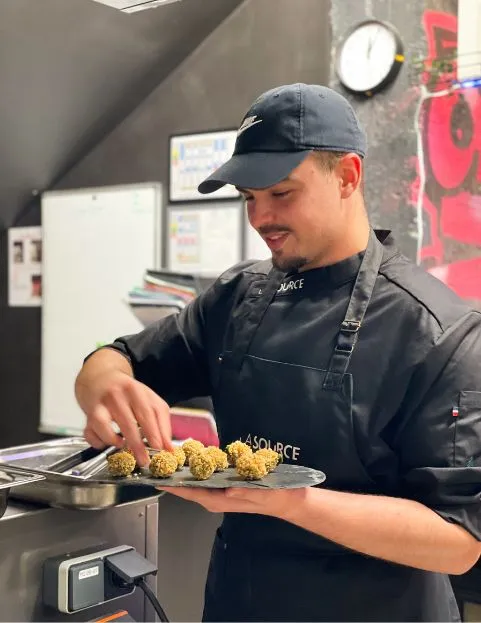 Un pâtissier découpe l'excédent de pâte autour d'un moule à tarte pour préparer une tarte au chocolat.